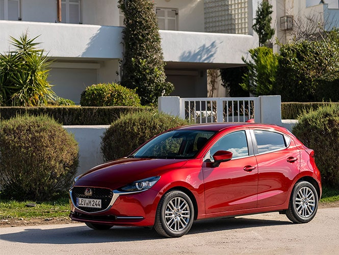 Mazda 2 Gebrauchtwagen Magmarot-Metallic vor einem Haus