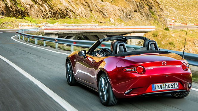 Mazda MX-5 Neuwagen in rot während der Fahrt von schräg hinten