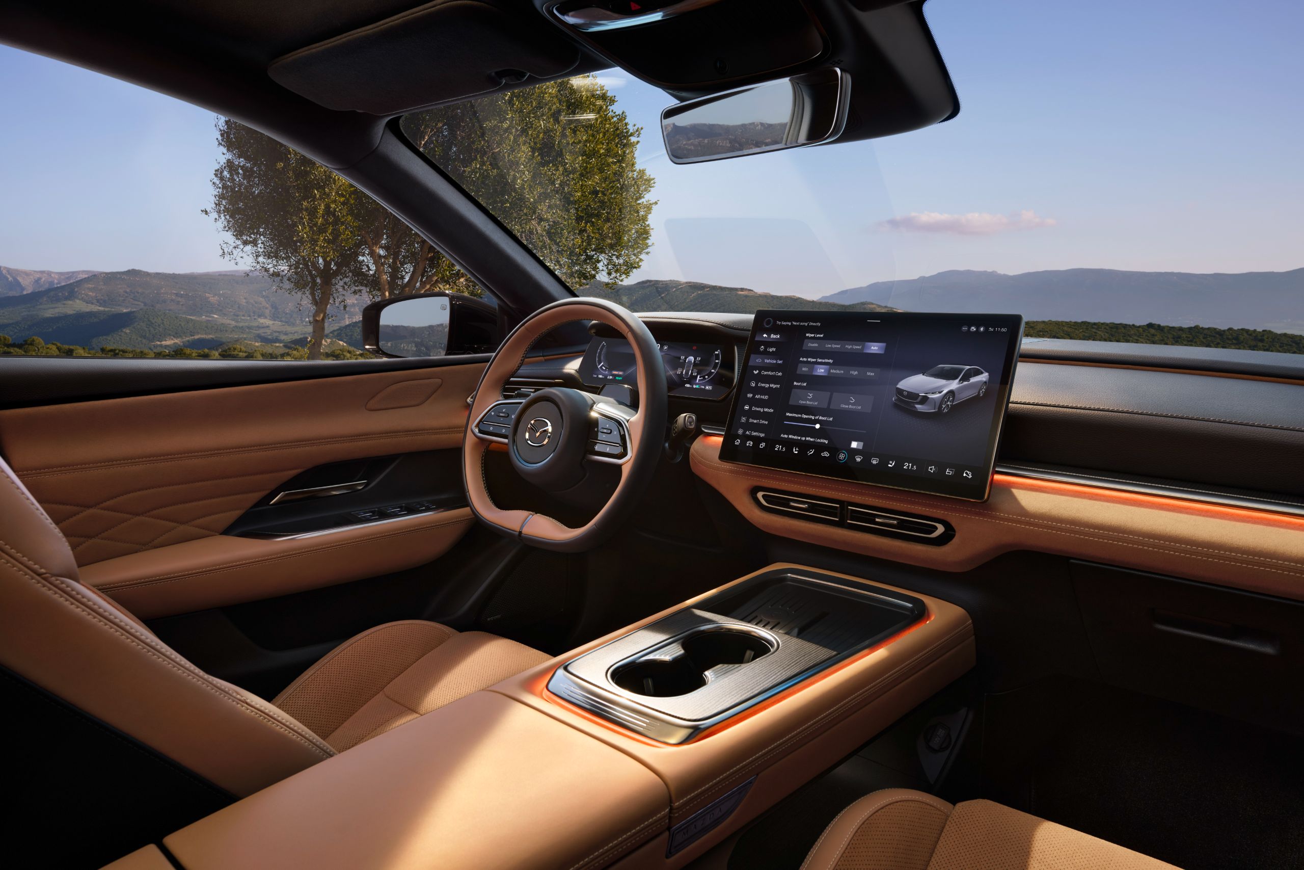 Innenraum des Mazda 6e mit brauner Lederausstattung, großem zentralen Touchscreen und digitalem Cockpit vor Panoramaausblick.