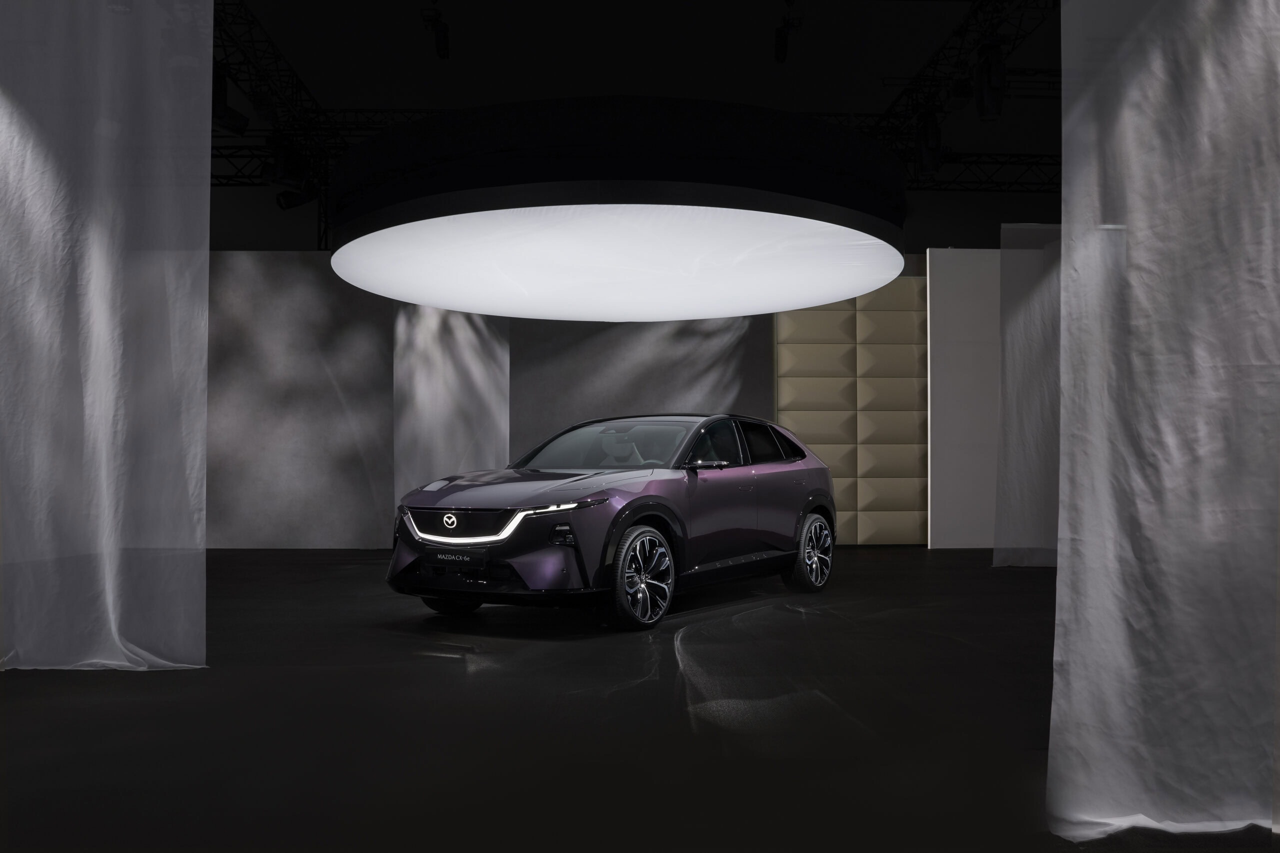 Mazda CX-6e auf einer Präsentationsfläche vor modernem Hintergrund